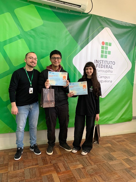 Estudantes Bernardo e Giovana, ao lado do professor Anderson Rocha, celebram a conquista na OBG